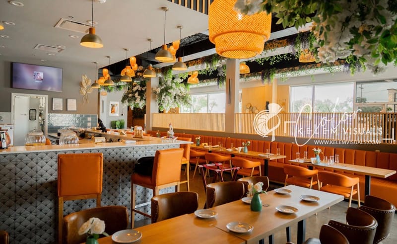 Interior of Injera & Beyond restaurant — warm, inviting dining room with hanging lights and greenery